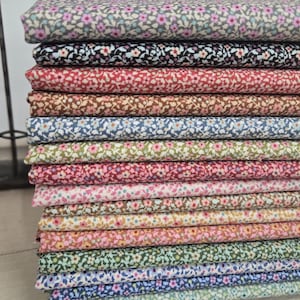 May include: A stack of various floral patterned fabric pieces. The fabrics feature small, colorful flower designs on a variety of backgrounds, including pink, red, blue, and green. The fabrics are neatly folded and stacked, showcasing the different patterns.
