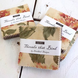 May include: Fabric squares with a floral pattern in shades of cream, red, and green. Each bundle is wrapped with a white label that reads "Threads that Bind by Blackbird Designs."