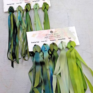 May include: Assortment of hand-dyed silk ribbon in shades of green, including Evening Sage, Green Mist, Evergreen, Spring Green, and Lime. The ribbon is 3.5 mm wide and comes in 2 yard lengths. The ribbon is displayed on a white card with the name of the colors and the brand "IBB & Ziney".