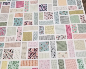 May include: A patchwork quilt with a variety of floral patterns in shades of pink, green, blue, and yellow. The quilt is made up of rectangular pieces of fabric sewn together to create a geometric design.