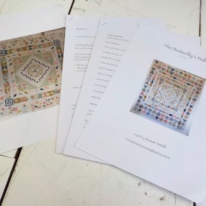 May include: Printed quilt pattern titled "The Butterfly's Ball" by Susan Smith. The pattern includes a color image of the quilt, featuring floral and geometric designs in pastel colors. Instructions are included on several white sheets.