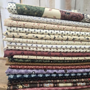 May include: A stack of folded fabric pieces in various colors and patterns. The fabrics include floral, geometric, and dotted designs in shades of cream, green, burgundy, navy, and brown. The fabrics are stacked on top of each other.