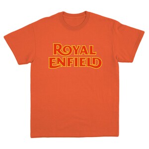 May include: A bright orange short-sleeved t-shirt featuring the text ROYAL ENFIELD printed across the chest in a bold, stylized red font with a thin yellow outline. The garment has a classic crew neckline and a standard straight-cut hem.