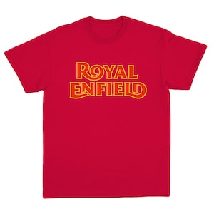 May include: A bright red short-sleeved t-shirt featuring the text ROYAL ENFIELD printed across the chest in a bold, stylized yellow font with a thin orange outline. The garment has a crew neckline and a standard fit with short sleeves.