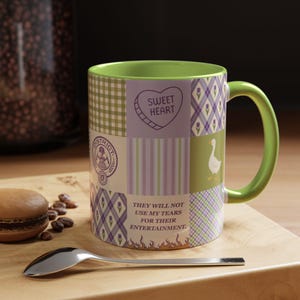 Op de afbeelding: Een keramische mok in patchwork-stijl met een groene handgreep en binnenkant. Het ontwerp bevat verschillende patronen en tekst, waaronder een hart met de tekst "Sweet Heart" en de zin "They will not use my tears for their entertainment."