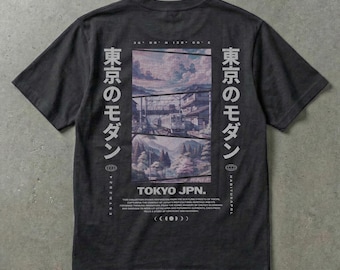 May include: Dark gray t-shirt with a graphic on the back featuring a landscape scene with a bridge and buildings. The text "TOKYO JPN." is below the graphic, with Japanese text on either side.