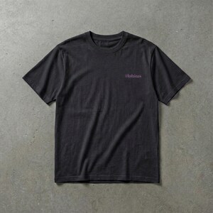May include: A dark gray t-shirt with short sleeves. The word "Habitus" is printed in a small, purple font on the upper chest area. The shirt is made of a soft material and is suitable for casual wear.