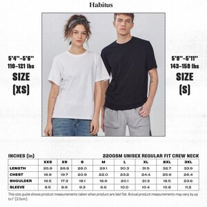 Puede incluir: Dos personas modelan camisetas unisex de cuello redondo, una blanca y otra negra. La imagen incluye una tabla de tallas con medidas en pulgadas. La tabla detalla las tallas de largo, pecho, hombro y manga. La marca "Habitus" est&aacute; en la parte superior.