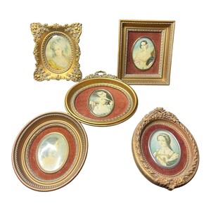 Puede incluir: Cinco marcos de pared decorativos con acabados dorados y detalles ornamentados. Cada marco contiene el retrato de una persona, con tres marcos colocados sobre fondos de terciopelo rojo. La colección incluye formas ovaladas y rectangulares.