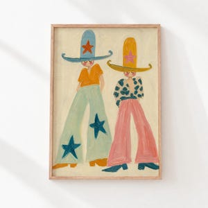 May include: A framed painting on a cream background depicting two figures wearing wide-brimmed hats. The left figure wears a blue hat with an orange star, an orange top, and light blue flared trousers with dark blue stars. The right figure wears a yellow hat with a pink star, a patterned top, and pink flared trousers.
