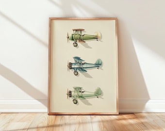 May include: A framed print featuring three vintage biplanes in shades of green and blue. The biplanes are depicted with detailed wings, propellers, and a classic design. The artwork is set against a cream-colored background, framed in a light brown wooden frame.
