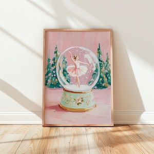 May include: Framed art print depicting a ballerina in a snow globe. The snow globe is set against a pink backdrop with green trees. The base of the snow globe is mint green with floral details. The ballerina wears a pink tutu.