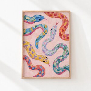 May include: A framed art print featuring a light pink background with multiple snakes painted in vibrant colours including blue, yellow, orange, and green. The snakes have visible brushstrokes and are depicted in various winding, curved positions.