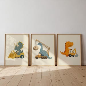 May include: Three framed art prints with dinosaur illustrations. One shows a blue dinosaur in a yellow digger. Another shows a blue dinosaur operating a crane. The third shows an orange dinosaur in a yellow digger.
