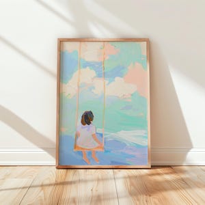 May include: A framed art print showing a person on a swing, viewed from behind. The painting uses pastel colours, including blue, pink, and green, to create a dreamy sky and water scene. The artwork is in a wooden frame.