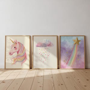 Könnte beinhalten: Drei gerahmte Aquarelldrucke. Der erste zeigt ein rosa Einhorn mit goldenem Horn und fließender Mähne. Der zweite zeigt eine Wolke, die Herzen regnen lässt. Der dritte zeigt einen goldenen Stern mit einem Regenbogen.