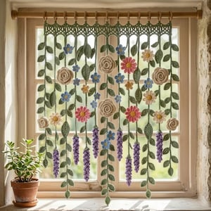 Puede incluir: Una cenefa de ganchillo para ventana con enredaderas colgantes de hojas verdes, rosas color crema, margaritas rosas, pequeñas flores azules y racimos morados tipo lavanda. La pieza cuelga de una barra de madera con anillas de madera.