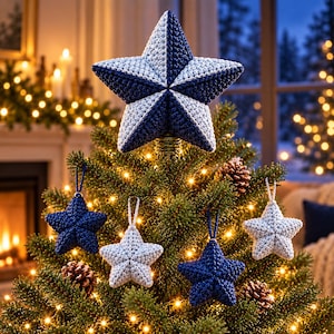 May include: A large, five-pointed star tree topper featuring a split design of dark navy blue and light gray crochet fabric, accompanied by four smaller, matching star-shaped ornaments hanging from the branches of a green pine tree.