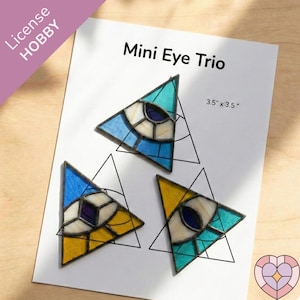 May include: Three stained glass triangular art pieces, each featuring an eye design. The pieces are in shades of blue, yellow, and teal, with white and purple accents. The text "Mini Eye Trio" and "3.5" x 3.5"" are visible.