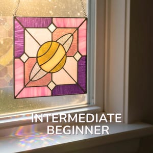 May include: Stained glass panel with a geometric design. The panel features a central yellow and white orb shape with a pink, purple, and white border. The text "INTERMEDIATE BEGINNER" is at the bottom.
