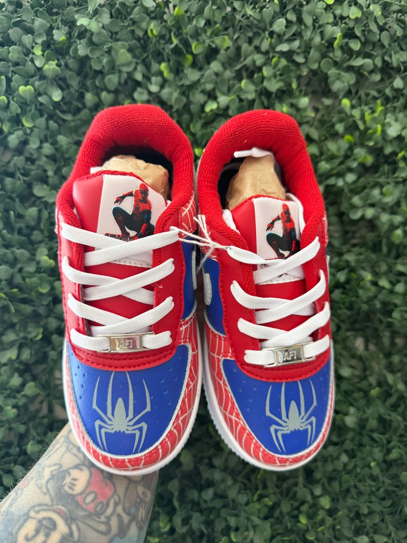 Puede incluir: Par de zapatillas rojas, azules y blancas con tem&aacute;tica de Spider-Man. Las zapatillas presentan un gr&aacute;fico de Spider-Man en el lateral y la leng&uuml;eta, con cordones blancos y suela blanca. Zapatos para ni&ntilde;os.