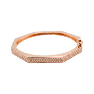 Pode incluir: Pulseira de bracelete em tom de ouro rosa com um design geom&eacute;trico octogonal. A pulseira &eacute; incrustada com pequenos cristais brilhantes ao longo das bordas. O fecho &eacute; vis&iacute;vel no lado direito. Joalharia.