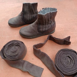 May include: Two pairs of brown felt boots with a fold-over top and a pair of brown felt boot straps.