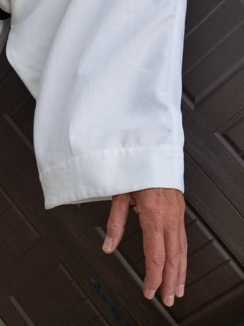 May include: A white long-sleeved shirt with a folded cuff. The shirt is made of a smooth, wrinkle-resistant fabric.