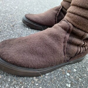 May include: Brown suede ankle boots with a fold-over cuff and a black rubber sole.