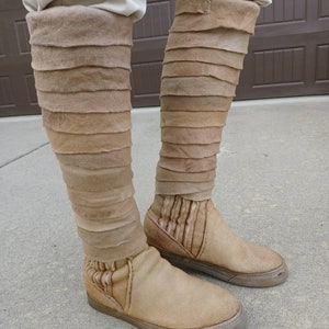 May include: A pair of tan leather boots with a layered design. The boots have a pointed toe and a thick sole.