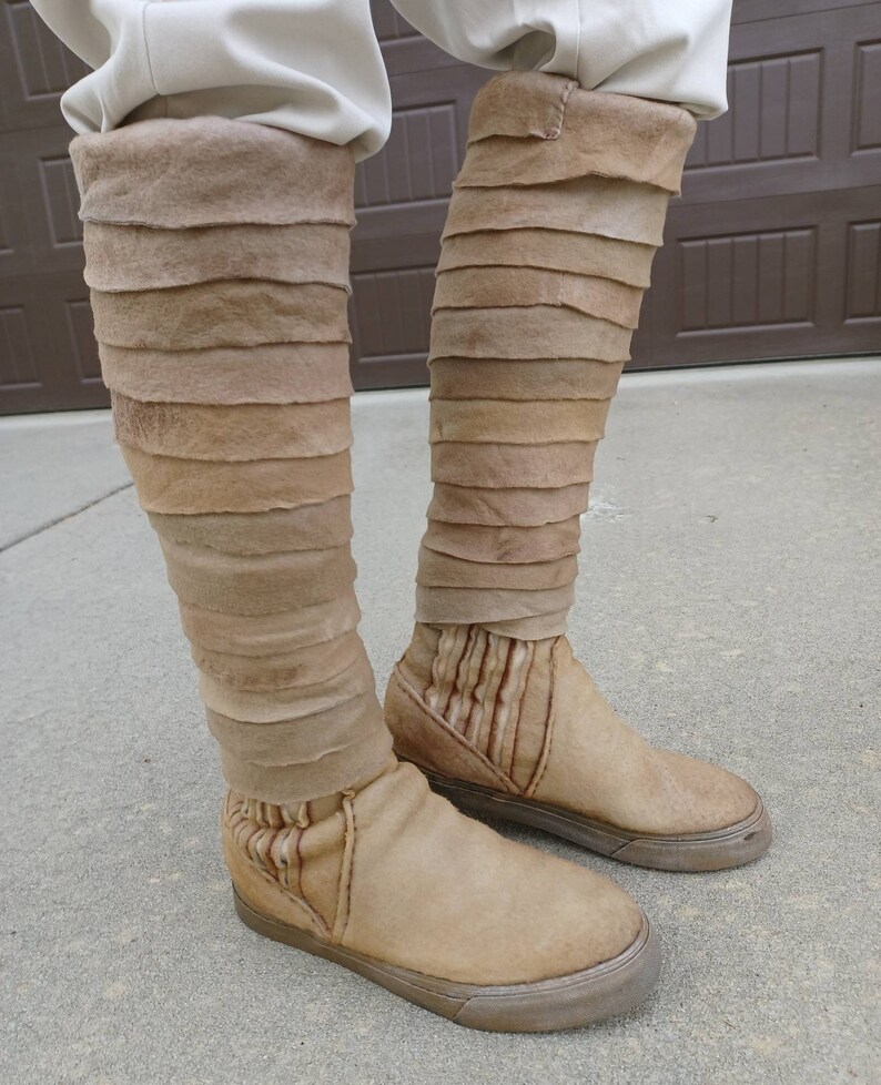 May include: A pair of tan leather boots with a layered design. The boots have a pointed toe and a thick sole.