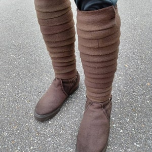 May include: Brown leather boots with a tall, folded cuff. The boots are made of a soft, suede-like material and have a rounded toe.