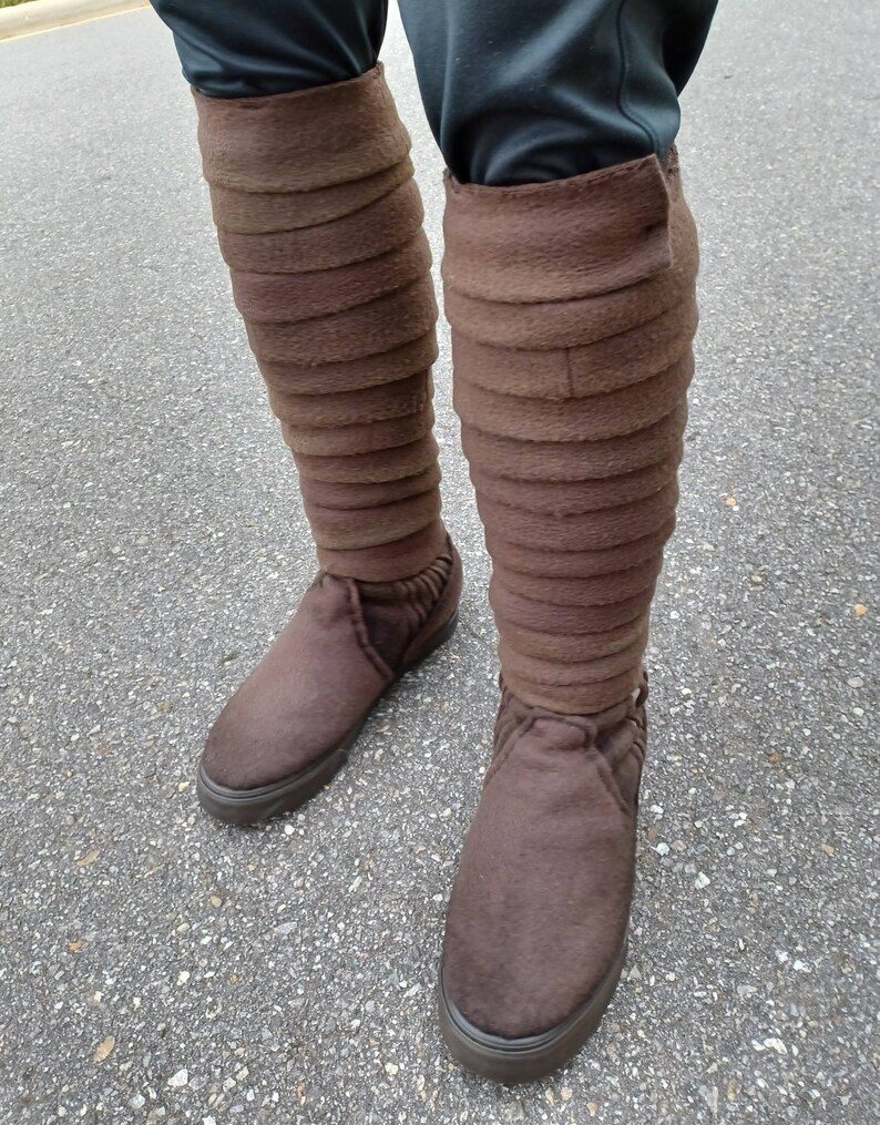 May include: Brown leather boots with a tall, folded cuff. The boots are made of a soft, suede-like material and have a rounded toe.
