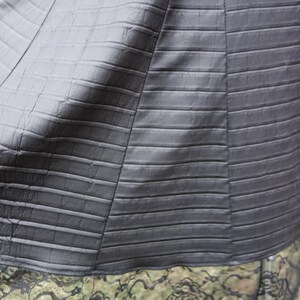 May include: A black skirt with a textured, alligator-like pattern. The skirt has a black lace trim.