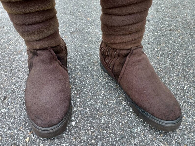 May include: A pair of brown suede boots with a fold-over cuff. The boots have a black rubber sole.