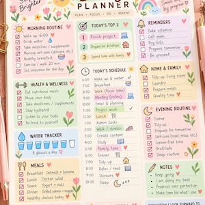 May include: A daily planner sheet with pastel illustrations of a sun, rainbow, and flowers. It features sections for morning, health, water, meals, gratitude, schedule, reminders, home, evening, notes, mood, and tomorrow's goals.