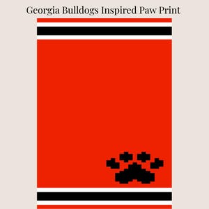 May include: A red and black paw print design with the text "Georgia Bulldogs Inspired Paw Print". The design features a large red background with a black paw print in the lower right corner and black and white stripes at the top and bottom.