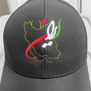 Puede incluir: Gorra de béisbol negra con un diseño bordado que presenta un mapa y una escritura en rojo, blanco, verde y amarillo. La gorra tiene una visera curva y un botón en la parte superior. El diseño está en la parte delantera.