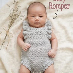 May include: A light gray crocheted baby romper featuring ruffled shoulder straps, a textured bodice pattern, and a scalloped leg opening with three small white buttons at the bottom. The text Baby Romper is printed in the upper right corner.