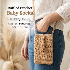 Peut inclure: Un sac bandoulière en crochet beige avec un motif texturé, un pompon central et une bandoulière assortie. Le texte sur l'image indique : Ruffled Crochet Baby Socks, Digital PDF Pattern, Step-by-Instructions, 1-3 months.