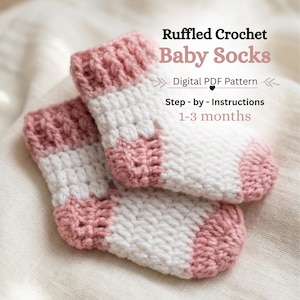 May include: A pair of white and dusty pink crocheted baby socks with a ruffled cuff design. The text on the image reads: Ruffled Crochet Baby Socks, Digital PDF Pattern, Step-by-Instructions, 1-3 months. The socks feature a textured stitch pattern.