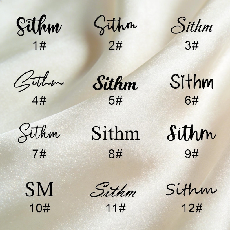 K&ouml;nnte beinhalten: Zw&ouml;lf schwarze Textdesigns auf wei&szlig;em Hintergrund. Das Wort "Sithm" ist in einer Schreibschrift geschrieben, jeweils mit einer Nummer von 1 bis 12. Die Buchstaben "SM" sind ebenfalls enthalten. Der Hintergrund ist ein weicher, strukturierter Stoff.