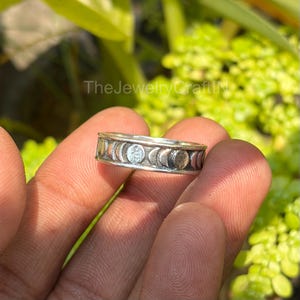 May include: A silver ring featuring a repeating moon phase design. The ring has a band of alternating crescent and full moon shapes. The text "The Jewelry Craft" is visible in the background.