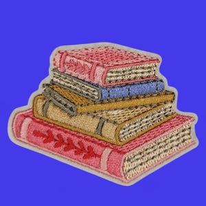 Könnte beinhalten: Gestickter Aufnäher mit einem Stapel Bücher in verschiedenen Farben. Die Bücher haben detaillierte Stickereien mit rosa, blauen und beigen Einbänden. Der Aufnäher hat einen weißen Rand auf blauem Hintergrund.