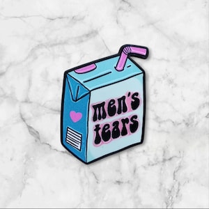 Könnte beinhalten: Hellblaue, saftkartonförmige Anstecknadel mit den Worten "men's tears" in schwarzer und rosa Schrift. Die Anstecknadel hat ein rosa Herz und einen rosa Strohhalm. Das Design ist schwarz umrandet.