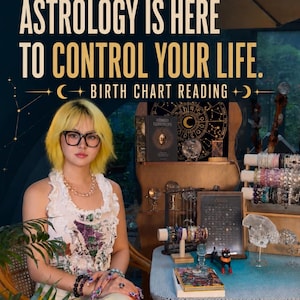 May include: A person with yellow hair wearing a white sleeveless top and a pearl necklace sits at a table with various crystal bracelets, a black cat figurine, a book titled Morbid Curiosities, and a birth chart reading sign with the text I DON'T BELIEVE ASTROLOGY IS HERE TO CONTROL YOUR LIFE.