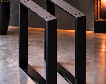 Könnte beinhalten: Ein Paar Tischbeine aus mattschwarzem Metall mit rechteckigem Rahmendesign. Jedes Bein verfügt über eine flache Montageplatte an der Oberseite mit vorgebohrten Löchern zur Befestigung. Die Struktur besteht aus vertikalen und horizontalen Stangen.