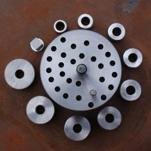 May include: A set of metal rings and a metal plate with multiple holes. The rings are of different sizes and are arranged around the plate.