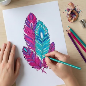 A lifestyle preview of a person's hands coloring a detailed feather illustration featuring vibrant teal, magenta, and purple patterns. This 60-page collection showcases high-quality bohemian line art set on a light wooden desk with art supplies, perfect for adult relaxation, mindful meditation, and printable Zen activities.