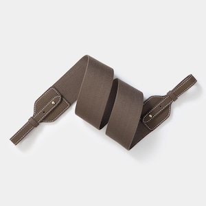 Può includere: Una tracolla marrone con estremità in pelle e un centro in tessuto intrecciato. Le estremità in pelle sono rifinite con cuciture bianche e un rivetto color oro. La tracolla è regolabile e mostrata su sfondo bianco.